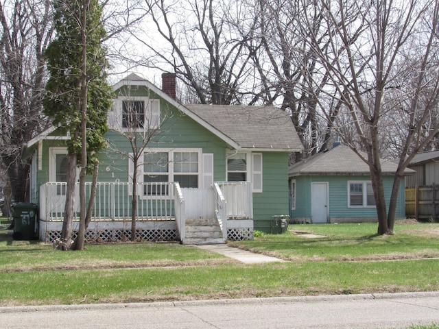 610 Grand Ave, Worthington, MN 56187 - view of front facade with a chimney, roof with shingles, a front lawn, and a porch