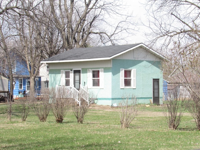 610 Grand Ave, Worthington, MN 56187 - view of front of home with a front yard, stucco siding, and roof with shingles