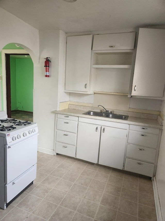 610 Grand Ave, Worthington, MN 56187 - kitchen with white gas range, a sink, light countertops, and white cabinetry