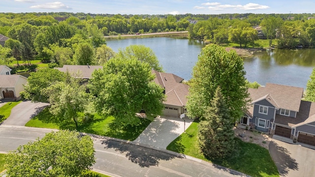 drone / aerial view of a nearby body of water and a heavily wooded area