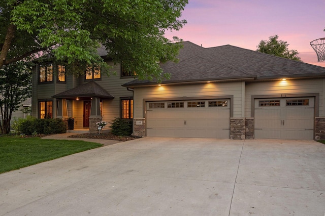 view of front facade featuring an attached garage, concrete driveway, stone siding, a front lawn, and a shingled roof