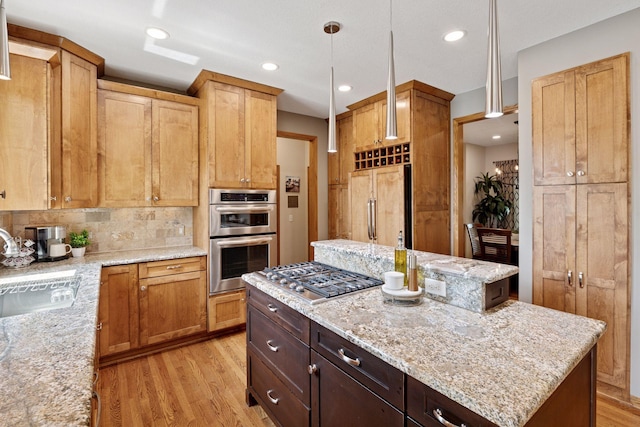 kitchen featuring stainless steel appliances, a sink, light wood-style flooring, light stone countertops, and recessed lighting