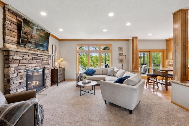living room with light colored carpet, a stone fireplace, recessed lighting, baseboards, and ornamental molding