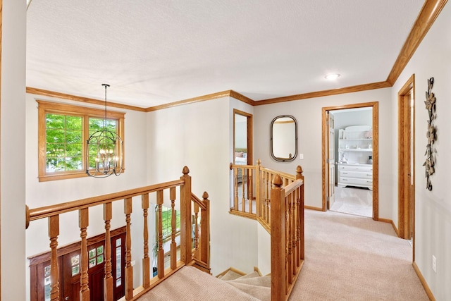 corridor with a chandelier, an upstairs landing, crown molding, baseboards, and light colored carpet