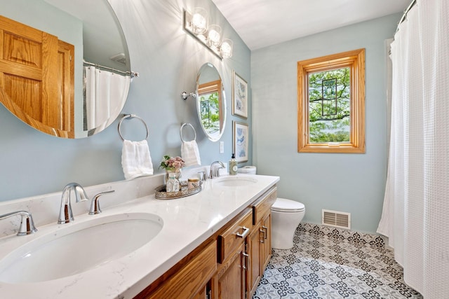 full bath featuring toilet and double vanity