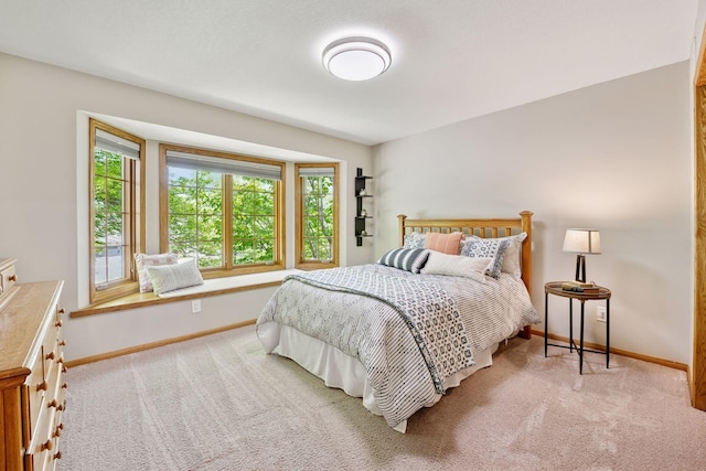 carpeted bedroom featuring multiple windows and baseboards