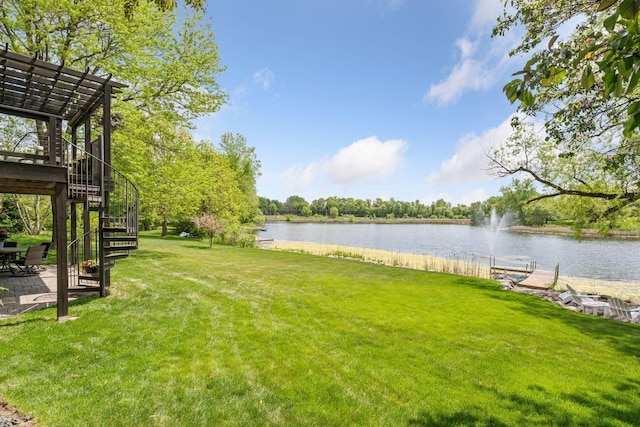 view of green lawn with a water view and stairway