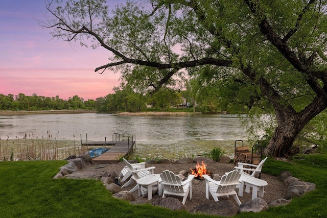 view of yard featuring an outdoor fire pit, a water view, and a boat dock