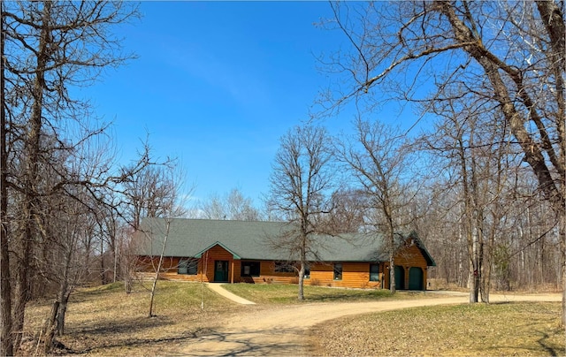 chalet / cabin featuring a shingled roof, dirt driveway, and a front yard