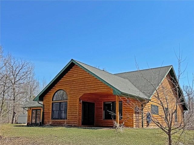 view of front of home with roof with shingles and a front yard