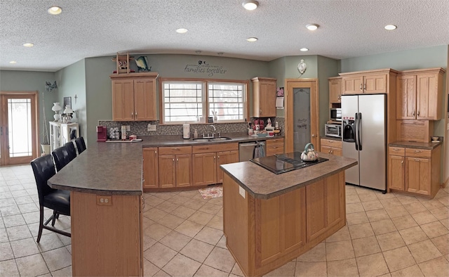 kitchen featuring a peninsula, a sink, appliances with stainless steel finishes, and tasteful backsplash