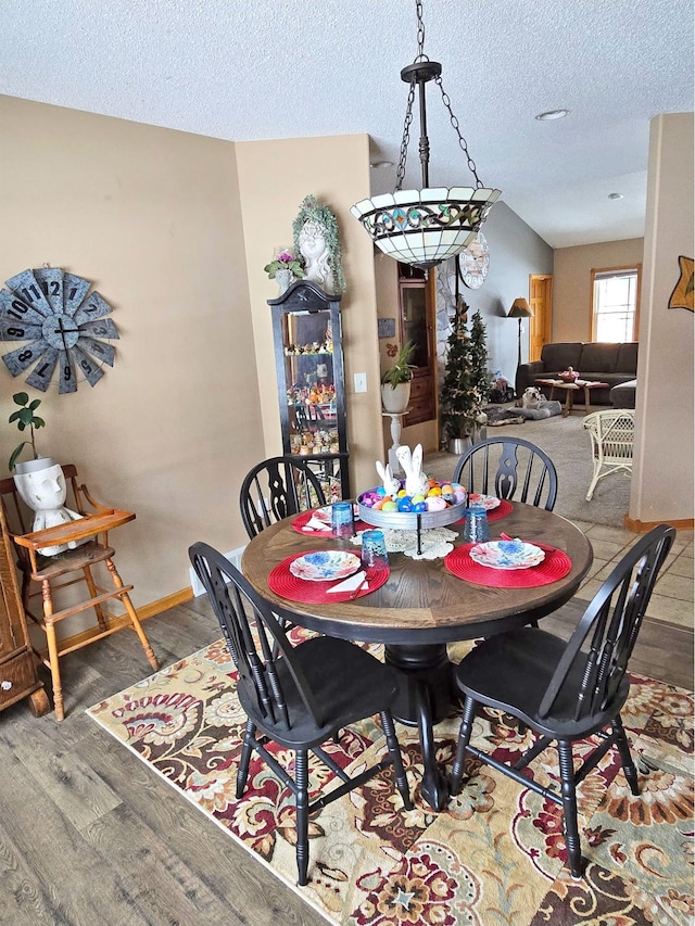 dining room with baseboards, wood finished floors, and a textured ceiling