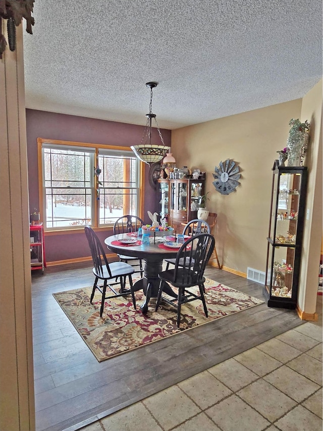 dining room featuring baseboards, visible vents, and a textured ceiling