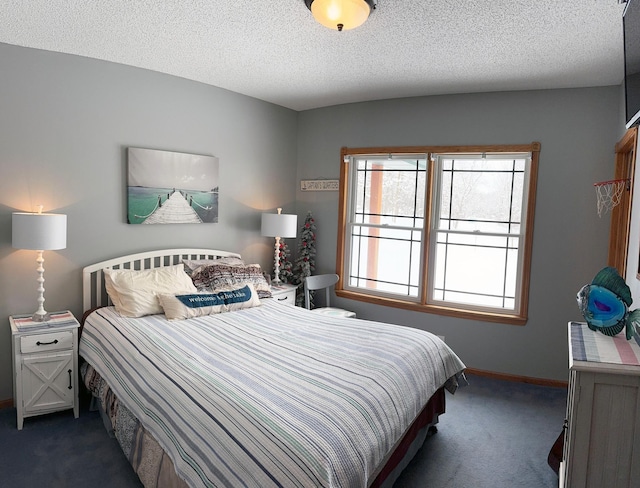 bedroom with dark colored carpet, a textured ceiling, and baseboards