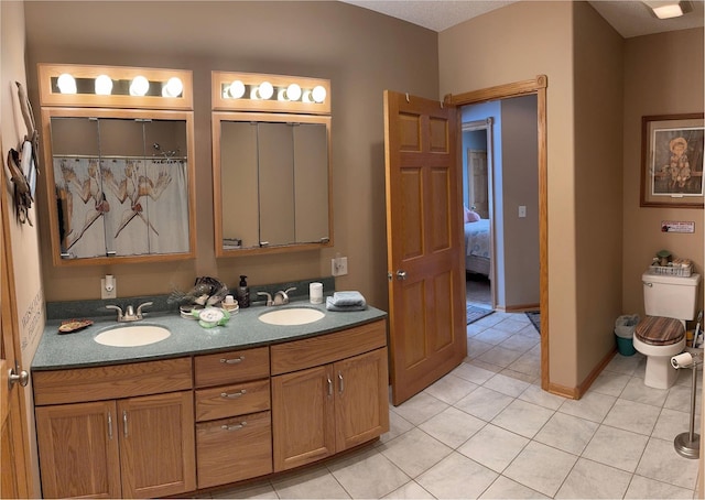 full bathroom with double vanity, tile patterned flooring, toilet, and a sink