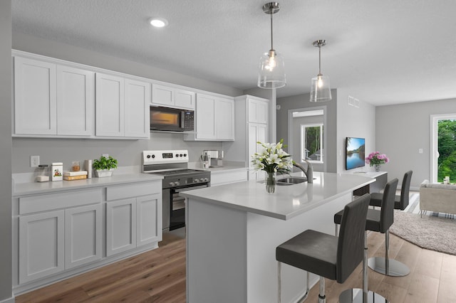 1595 76th St W, Inver Grove Heights, MN 55077 - kitchen with black microwave, stainless steel electric range, a sink, wood finished floors, and a breakfast bar area