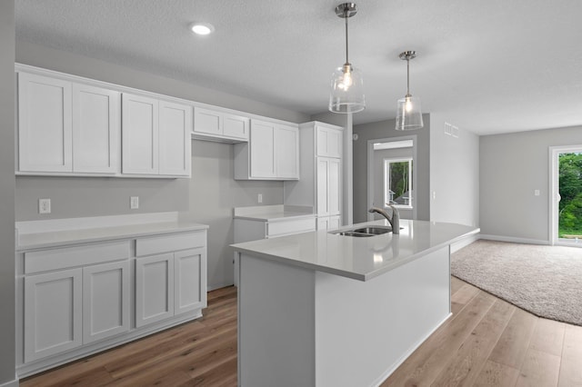 1595 76th St W, Inver Grove Heights, MN 55077 - kitchen with a sink, wood finished floors, white cabinetry, a kitchen island with sink, and a textured ceiling