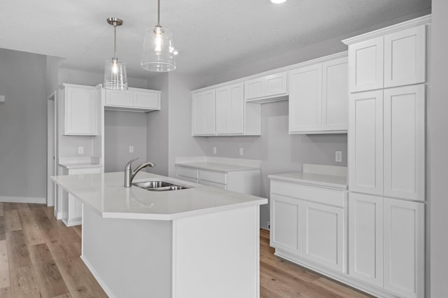 1595 76th St W, Inver Grove Heights, MN 55077 - kitchen with a sink, a kitchen island with sink, light wood-style floors, white cabinets, and pendant lighting