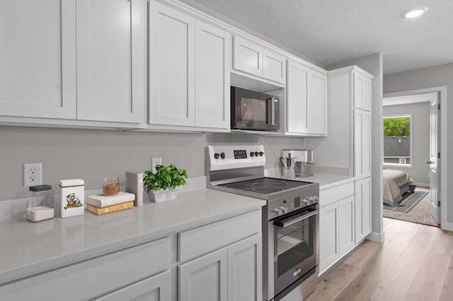 1595 76th St W, Inver Grove Heights, MN 55077 - kitchen featuring stainless steel range with electric stovetop, white cabinets, light countertops, light wood-style flooring, and recessed lighting