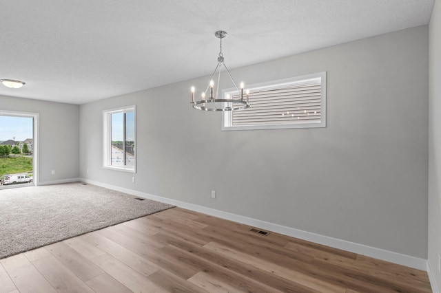 1595 76th St W, Inver Grove Heights, MN 55077 - empty room featuring a chandelier, baseboards, wood finished floors, and a textured ceiling