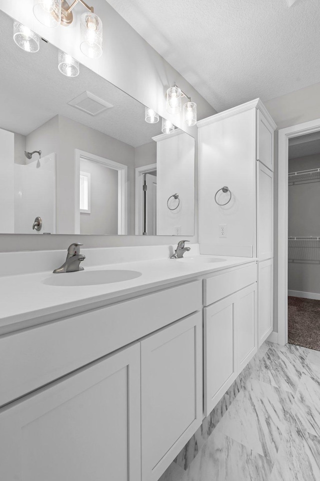 1595 76th St W, Inver Grove Heights, MN 55077 - bathroom featuring double vanity, marble look tile flooring, a textured ceiling, and a spacious closet