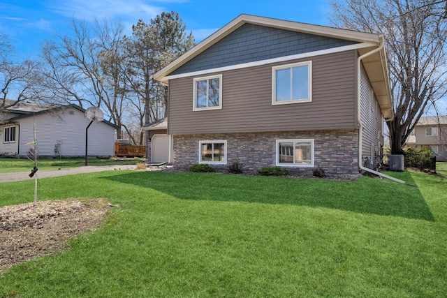 view of front of property featuring a front yard, stone siding, and central air condition unit