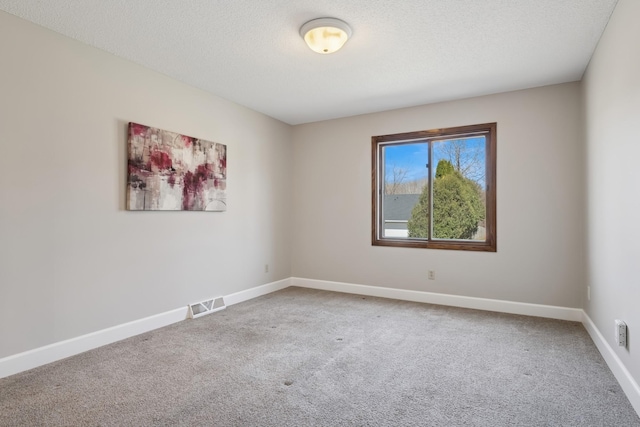 spare room featuring baseboards, visible vents, a textured ceiling, and carpet flooring