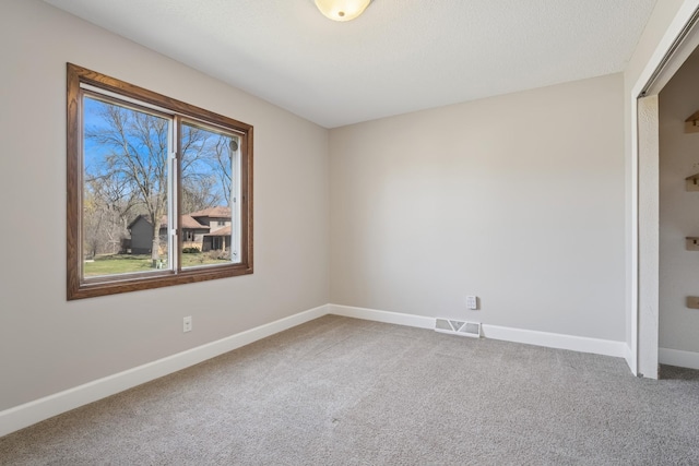 carpeted empty room featuring baseboards and visible vents