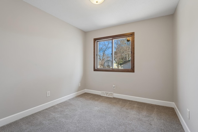 carpeted spare room with visible vents and baseboards