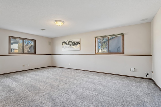 carpeted spare room featuring baseboards, a healthy amount of sunlight, and visible vents