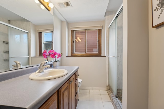bathroom with visible vents, toilet, vanity, tile patterned floors, and a stall shower