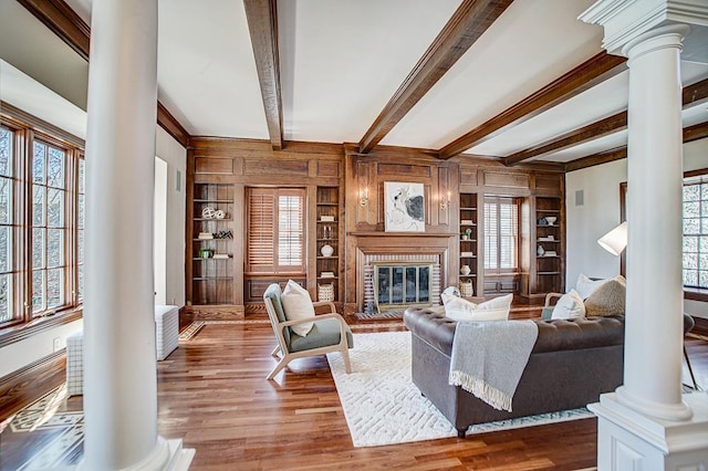 4927 Lake Ave, White Bear Lake, MN 55110 - living room featuring a fireplace, wood walls, built in shelves, decorative columns, and wood finished floors