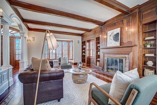 4927 Lake Ave, White Bear Lake, MN 55110 - living area featuring built in features, a brick fireplace, beamed ceiling, dark wood-style floors, and ornate columns