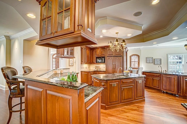 4927 Lake Ave, White Bear Lake, MN 55110 - kitchen featuring crown molding, built in appliances, a chandelier, brown cabinetry, and an island with sink