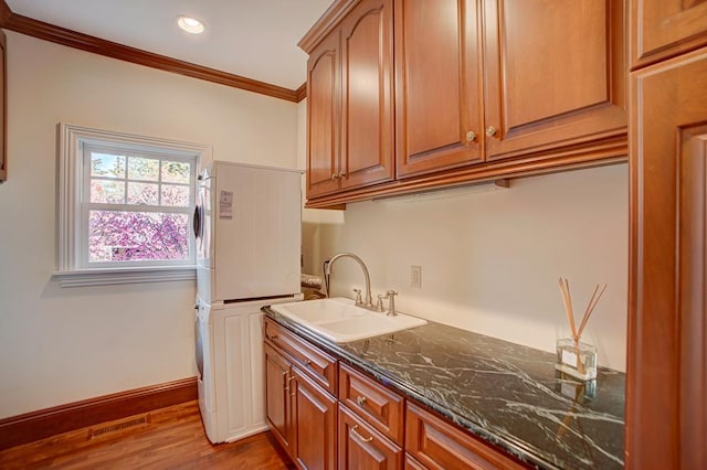 4927 Lake Ave, White Bear Lake, MN 55110 - kitchen with a sink, stacked washing maching and dryer, wood finished floors, visible vents, and ornamental molding