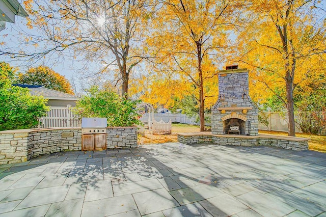 4927 Lake Ave, White Bear Lake, MN 55110 - view of patio / terrace with an outdoor kitchen, a fenced backyard, a grill, and an outdoor stone fireplace