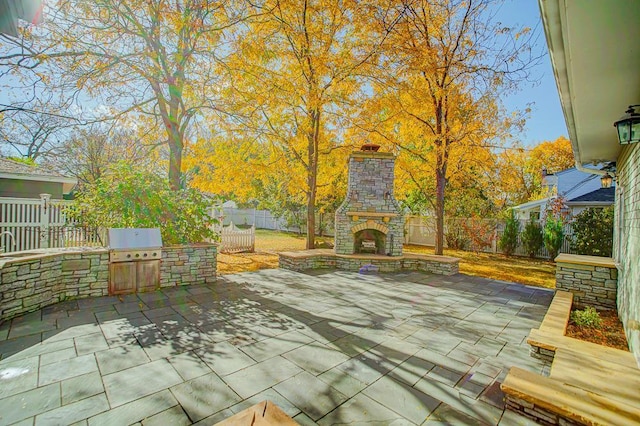 4927 Lake Ave, White Bear Lake, MN 55110 - fenced backyard with an outdoor stone fireplace, a patio, and an outdoor kitchen