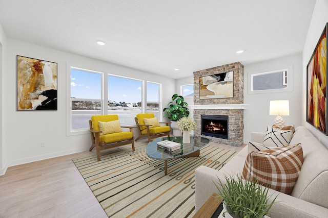 living room featuring recessed lighting, a fireplace, a water view, light wood-style flooring, and baseboards