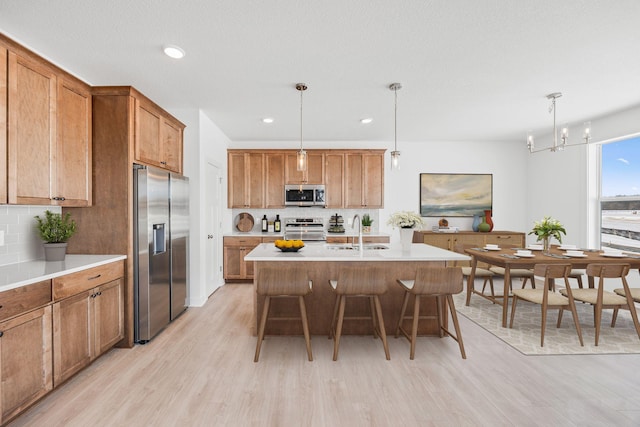kitchen with decorative backsplash, a sink, a breakfast bar, light wood-style floors, and stainless steel appliances