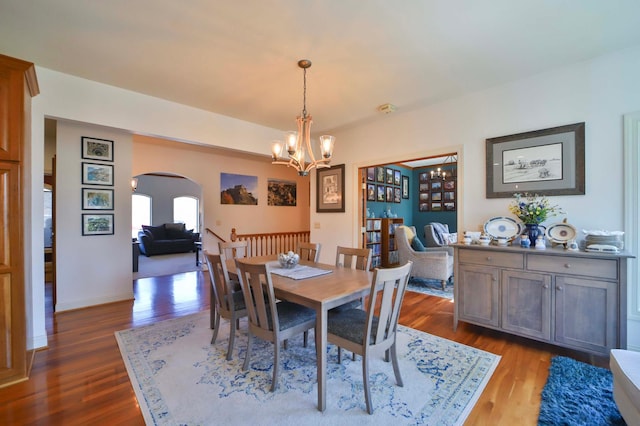 6203 Fairfax Ct, Baxter, MN 56425 - dining space featuring arched walkways, a chandelier, dark wood-type flooring, and baseboards