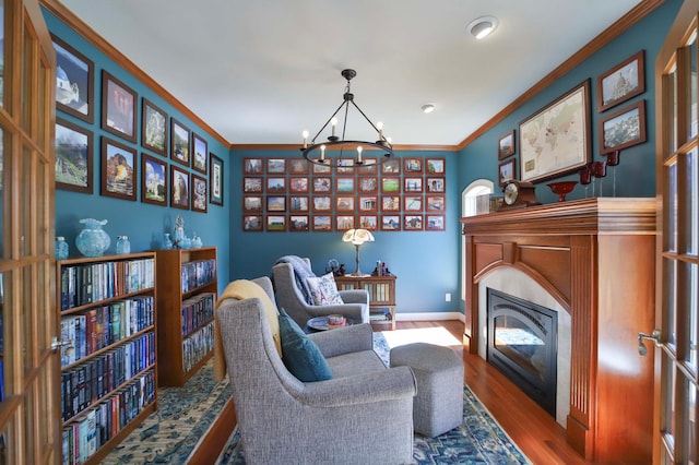 6203 Fairfax Ct, Baxter, MN 56425 - sitting room featuring a chandelier, a glass covered fireplace, wood finished floors, ornamental molding, and baseboards