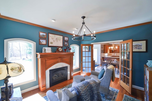 6203 Fairfax Ct, Baxter, MN 56425 - living room featuring a chandelier, baseboards, a glass covered fireplace, healthy amount of natural light, and crown molding