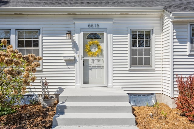 doorway to property featuring roof with shingles