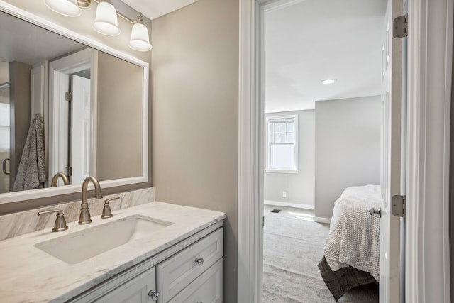 ensuite bathroom featuring baseboards, vanity, and recessed lighting