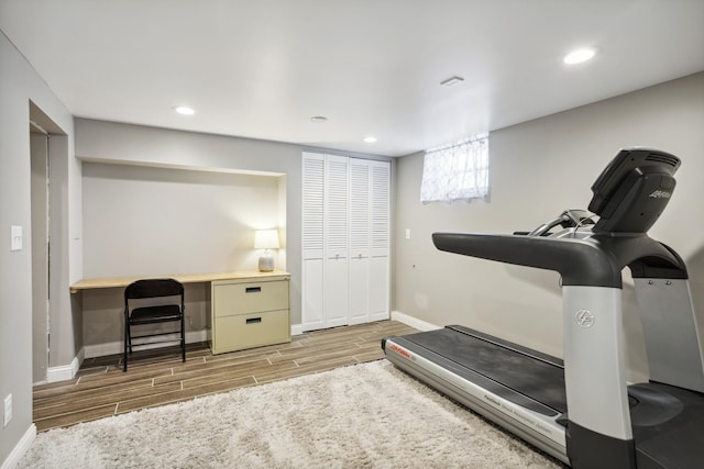 exercise area featuring wood finished floors, baseboards, and recessed lighting