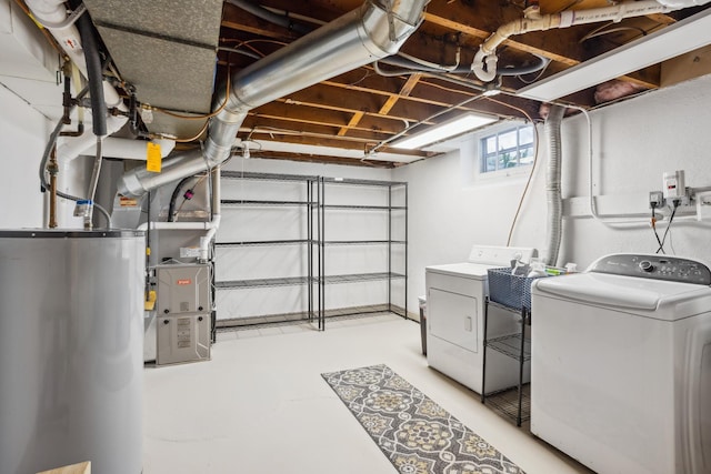 laundry area with gas water heater, washer and dryer, and heating unit