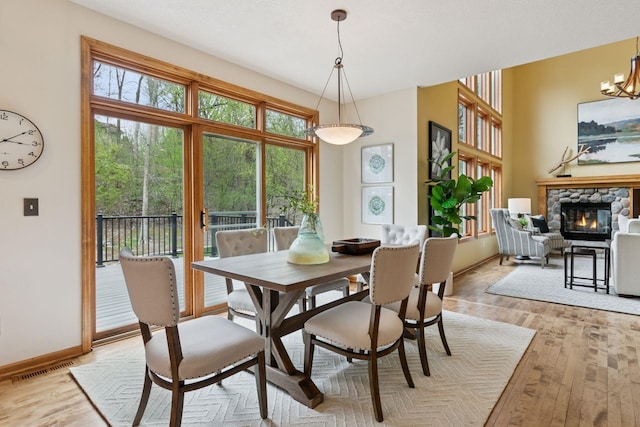 4633 Stonecliffe Dr, Eagan, MN 55122 - dining space featuring light wood-type flooring, a stone fireplace, a chandelier, and baseboards