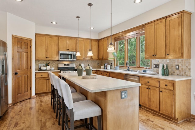 4633 Stonecliffe Dr, Eagan, MN 55122 - kitchen with appliances with stainless steel finishes, light wood finished floors, a center island, a breakfast bar area, and recessed lighting