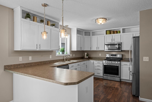 kitchen featuring a sink, a peninsula, stainless steel appliances, white cabinetry, and dark wood-type flooring