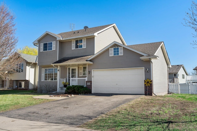 traditional home with fence, roof with shingles, a front lawn, a garage, and driveway
